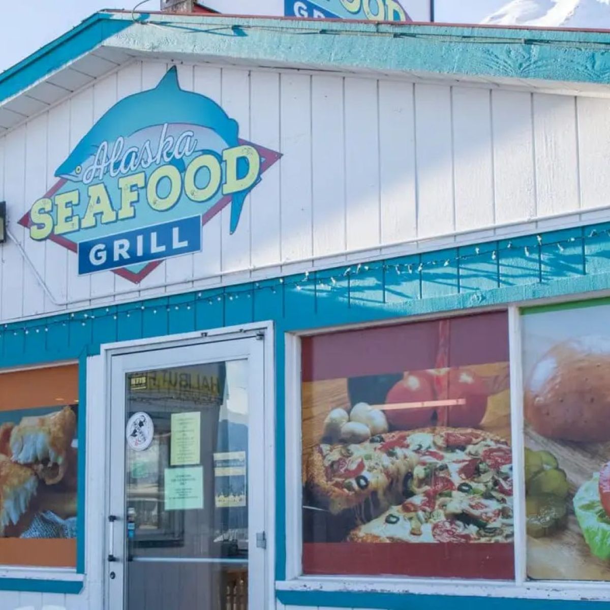 Exterior of Alaska Seafood Grill with food images on windows.